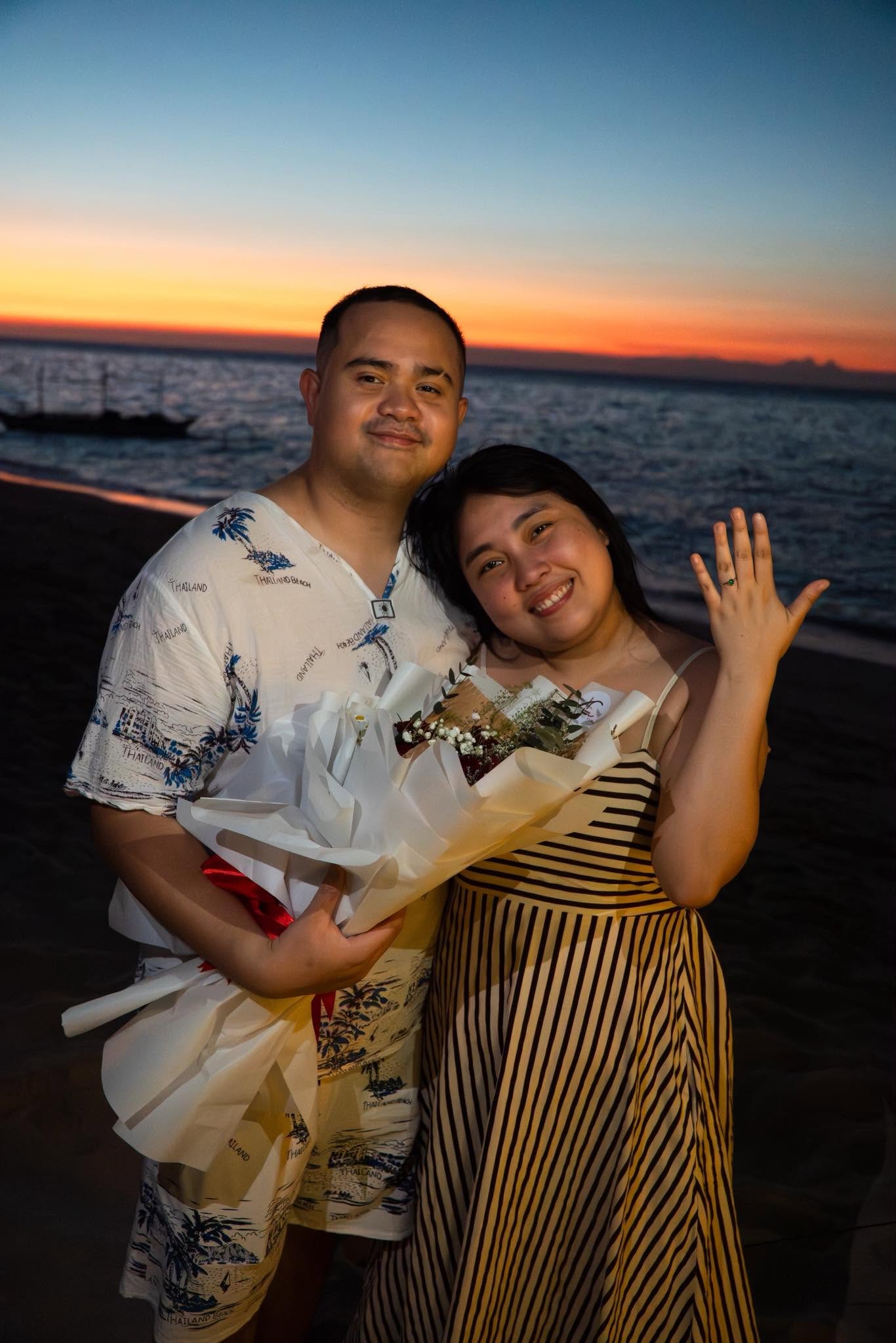 A couple celebrating together by the ocean at sunset